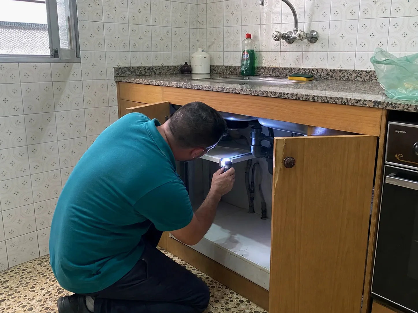Técnico de GarrigaPlagas inspeccionando una cocina con linterna